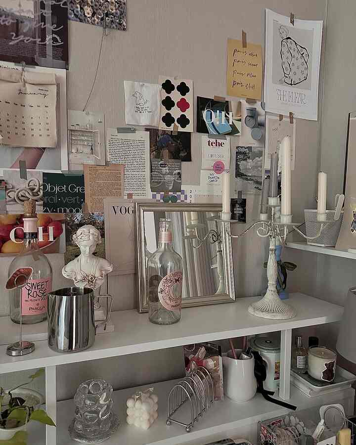 Cozy interior space with white and silver tones featuring shelves adorned with various objets and candles