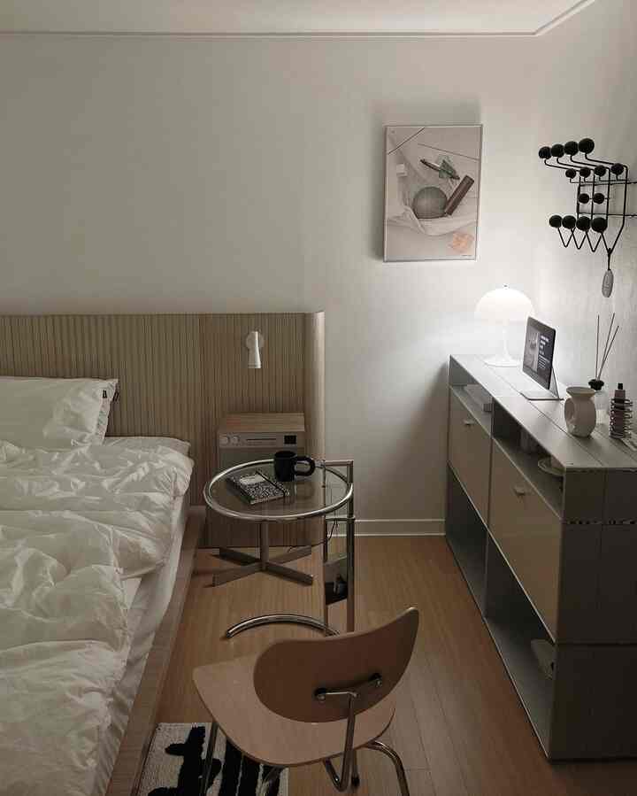 白い壁とベッド、ナチュラルな木目調の床と家具が配置されたモダンな寝室の雰囲気のあるインテリア