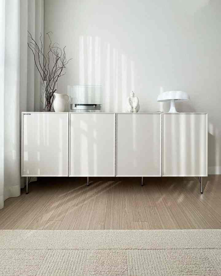 White and wood-tone living room featuring a modern cabinet and natural decorative elements creating a harmonious space