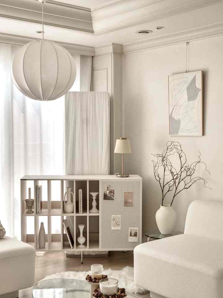 A white and beige toned living room featuring a minimalist Archive open cabinet styled with vases and candlesticks, embodying a simple Nordic interior
