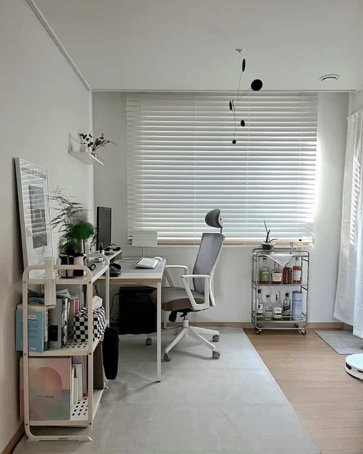 Bright study with white and wood tones, featuring a desk and office chair, illuminated by natural light through white blinds