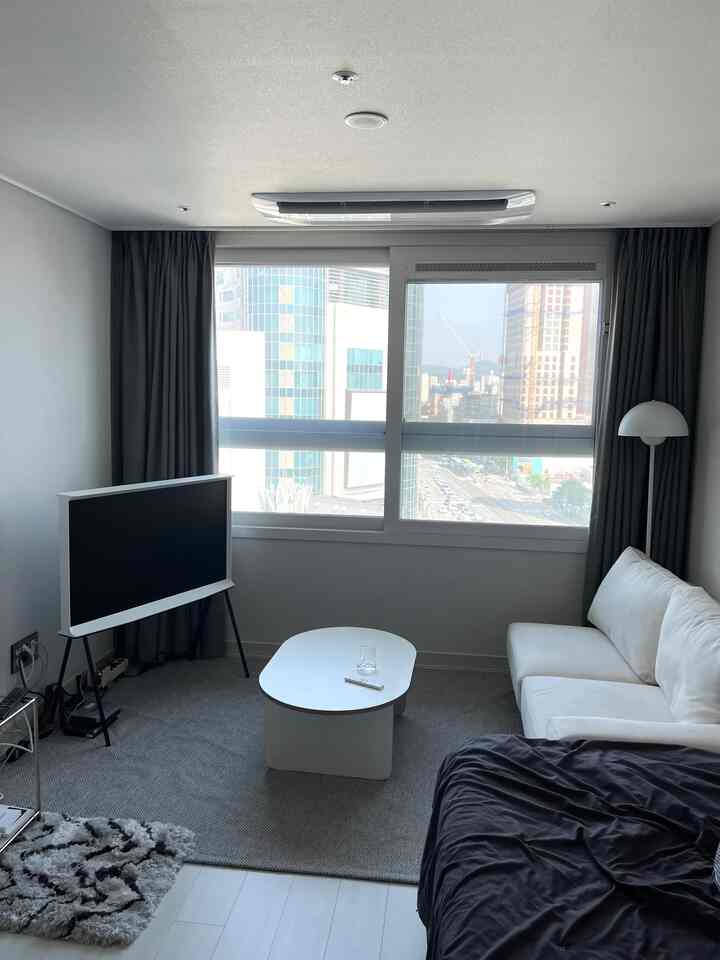Modern living room with gray and white tones, featuring a white coffee table center and white sofa on the right in a bright, clean setting