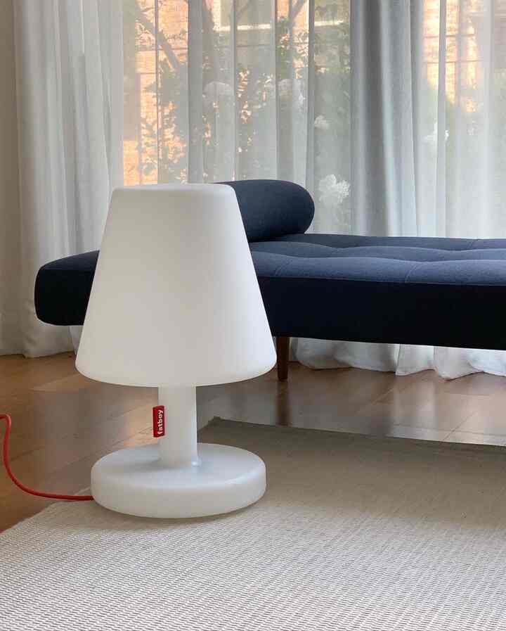 白とネイビートーンのリビングルーム、ネイビーのソファと白いテーブルランプが配置された落ち着いた印象の空間