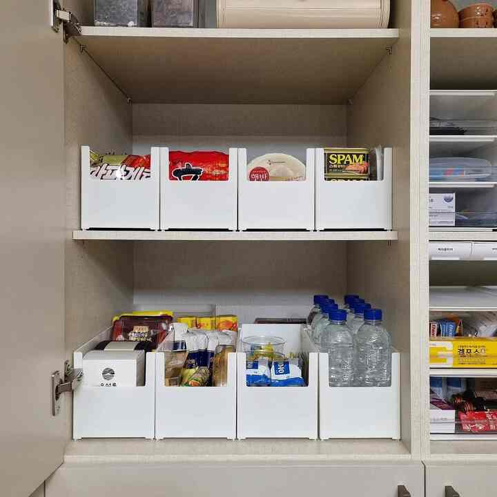 白い収納ボックスと様々な食料品が整理された整然としたキッチンのパントリー収納棚