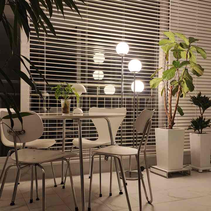 A white-toned dining room featuring modern natural dining chairs and floor lamps, creating a clean and cozy atmosphere