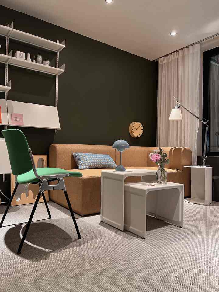 Mid-Century Modern living room with brown sofa, white nested tables, and a green accent chair