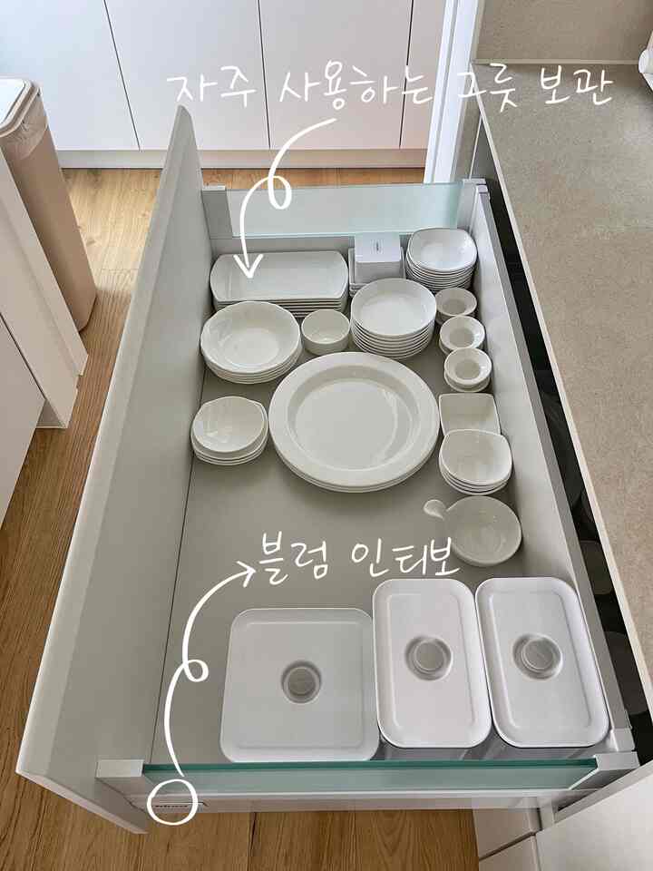 白を基調としたキッチンの引き出し内に整然と並べられたさまざまなサイズの食器のある雰囲気のあるインテリア