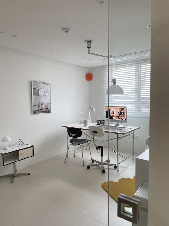 Bright white toned study room featuring a desk and two office chairs with minimalistic interior design