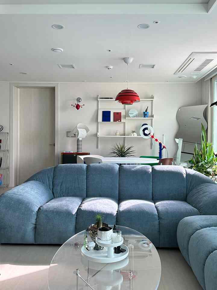 Living room with blue sofa and red pendant light against white walls, featuring contemporary mid-century modern style