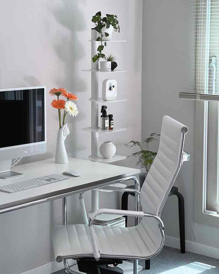 白を基調とした書斎、ホワイトデスクとチェア、窓際に植物と棚が配置されたミニマルなホームオフィス空間