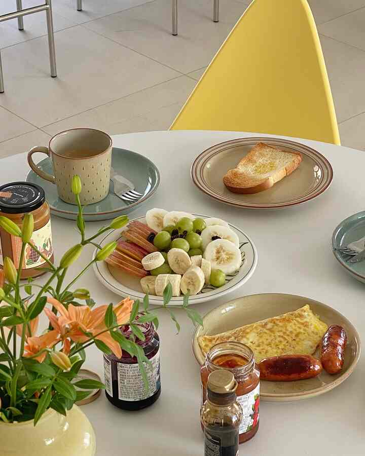 Cozy home cafe setting with a round white dining table featuring assorted plates and breakfast items alongside a yellow chair
