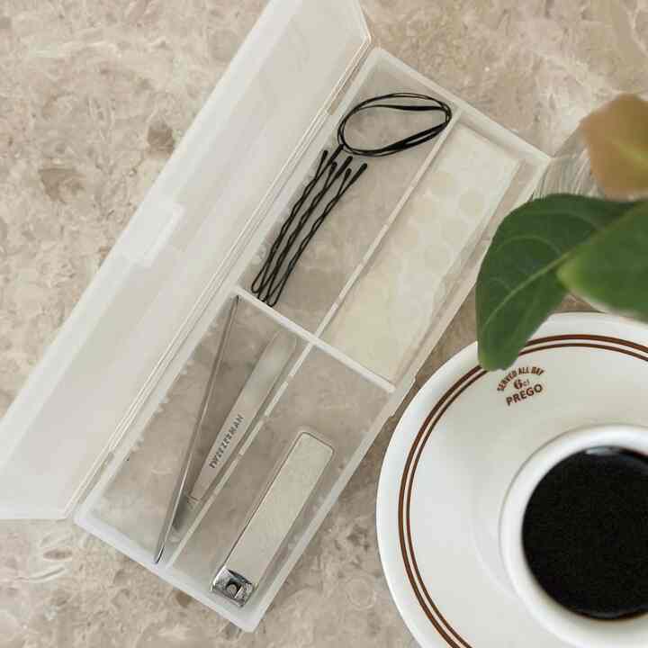 Clean minimal powder room featuring a transparent plastic storage box and a coffee cup on the vanity