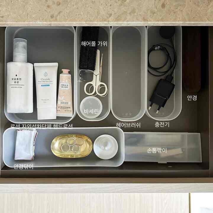 Monotone built-in closet drawer featuring neatly organized vanity items and a nail clipper in a clean space