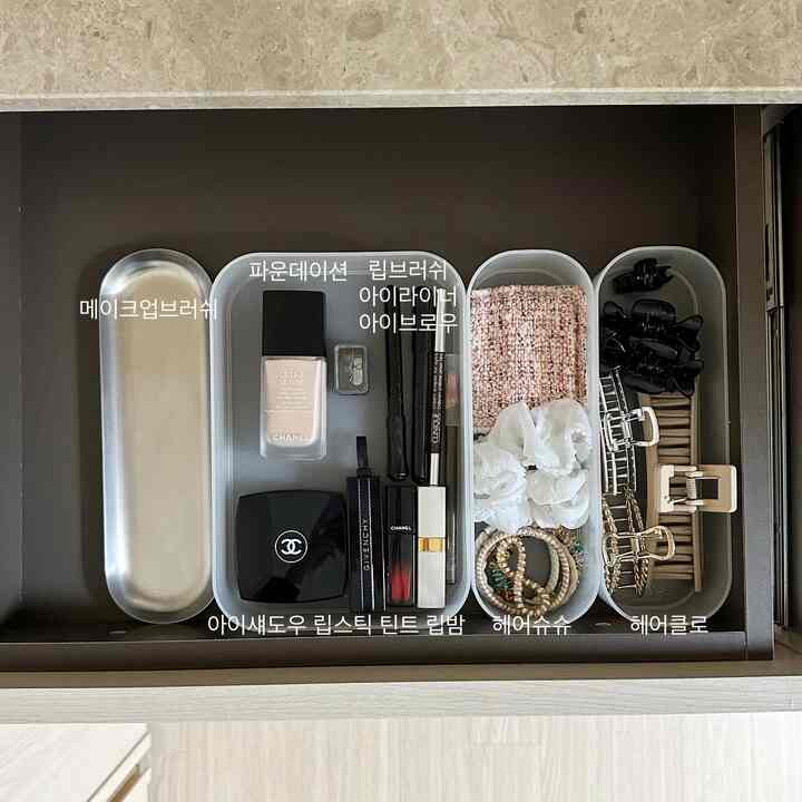 White-toned powder room drawer interior featuring organized cosmetics and hair accessories in a neat minimal space