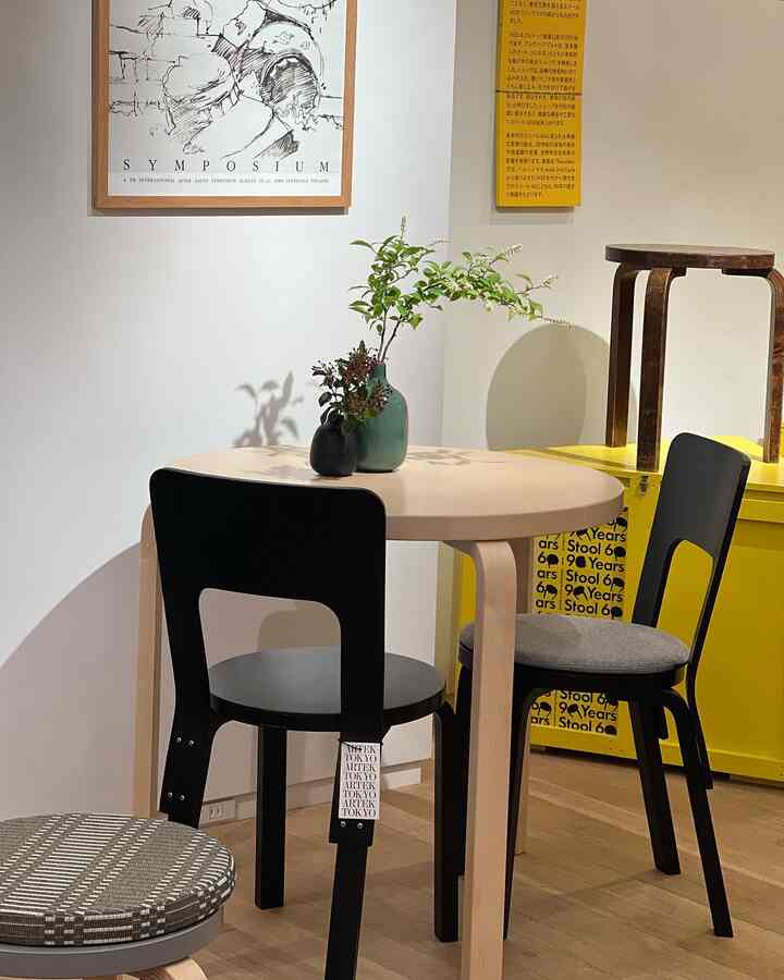 Natural wood-toned round dining table paired with black chairs in a cozy cafe style dining room