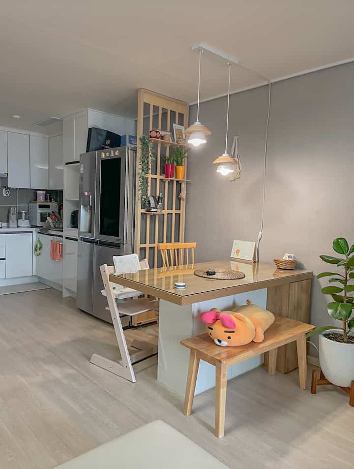 白と木目調が調和したキッチンとダイニング、子供用椅子を備えた温かみのある自然な雰囲気の空間