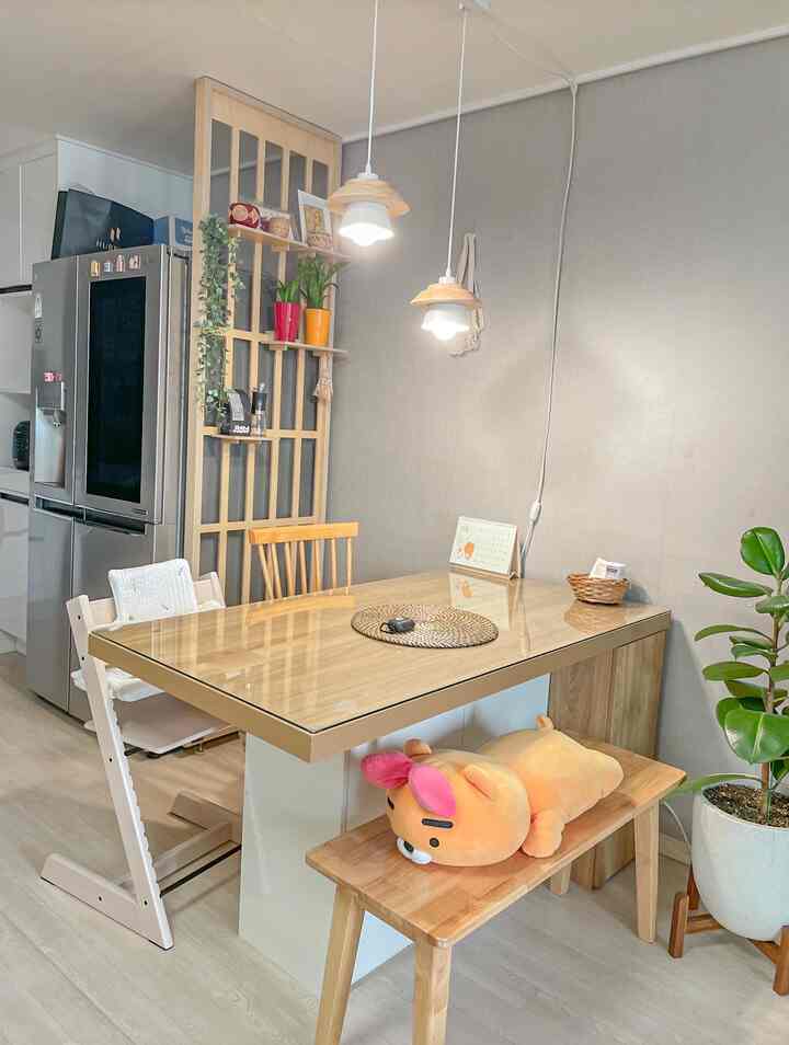A cozy natural wood-tone dining room featuring a wooden dining table, bench, and kids' high chair centered for a warm atmosphere