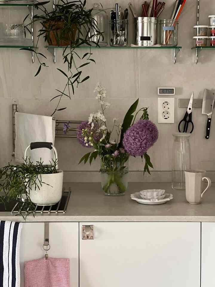 Natural tone kitchen featuring a central vase of flowers and plants with clean and practical layout
