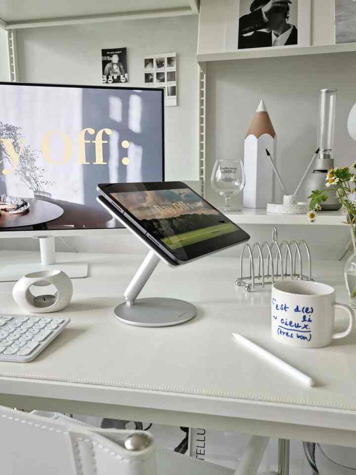 白とグレーのトーンのホームオフィス、アイパッドスタンドやマグカップなどが配置された印象的なモダンなインテリア