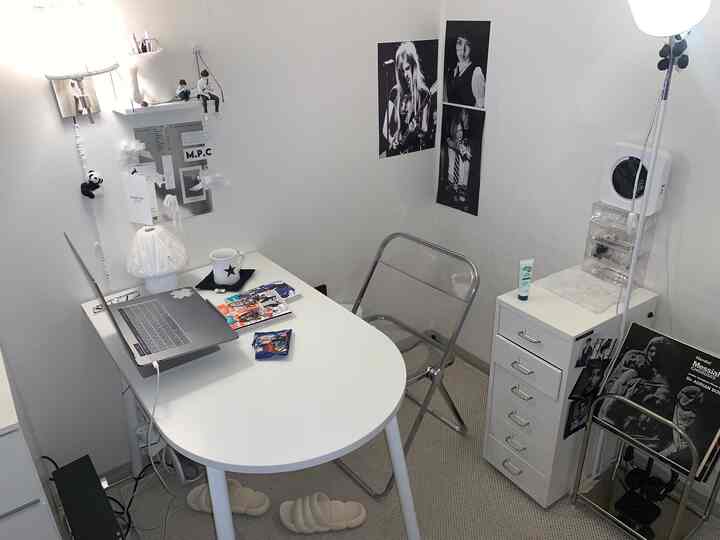 A small, white-toned room featuring a simple desk and transparent chair in a modern home office setup