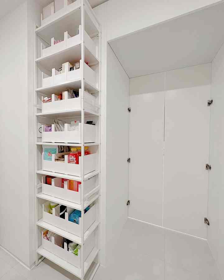 White-toned auxiliary kitchen interior featuring a slim storage cabinet neatly placed in a wall gap, creating a clean and compact area