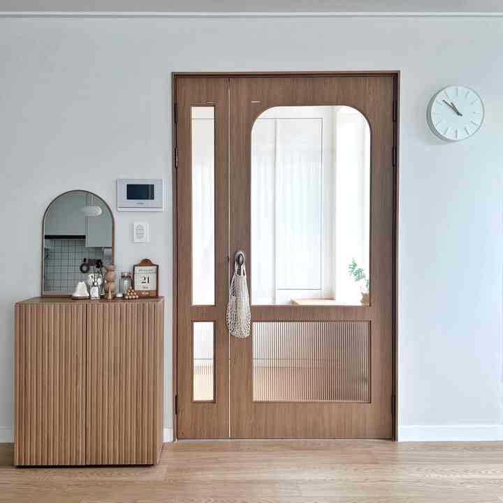 Clean entrance area featuring white walls, wood-tone entrance door, and Tembaboard storage cabinet