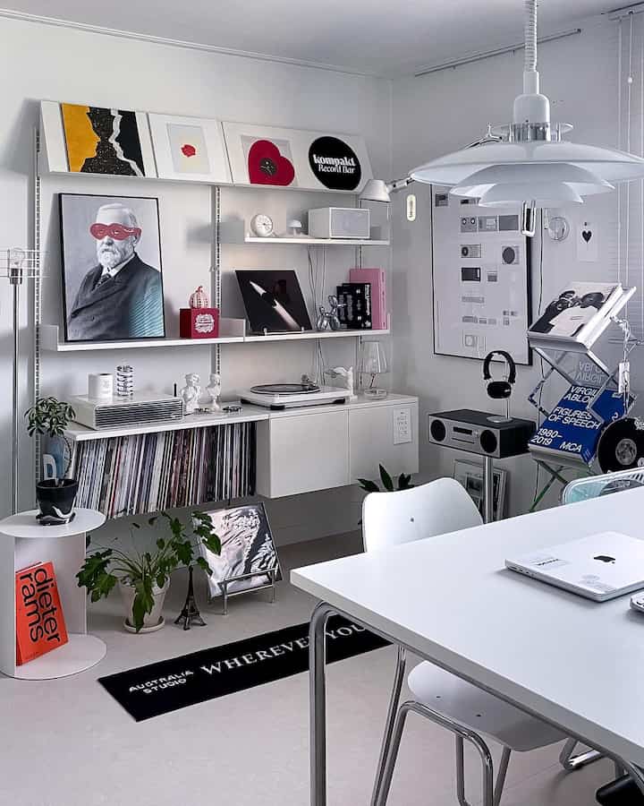White-toned living room featuring wall shelves and mid-century modern furniture with a stylish blend of music and workspace elements
