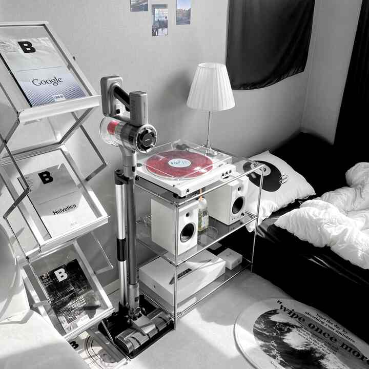 Monotone minimalist small bedroom featuring a cordless vacuum cleaner and turntable with simple decor
