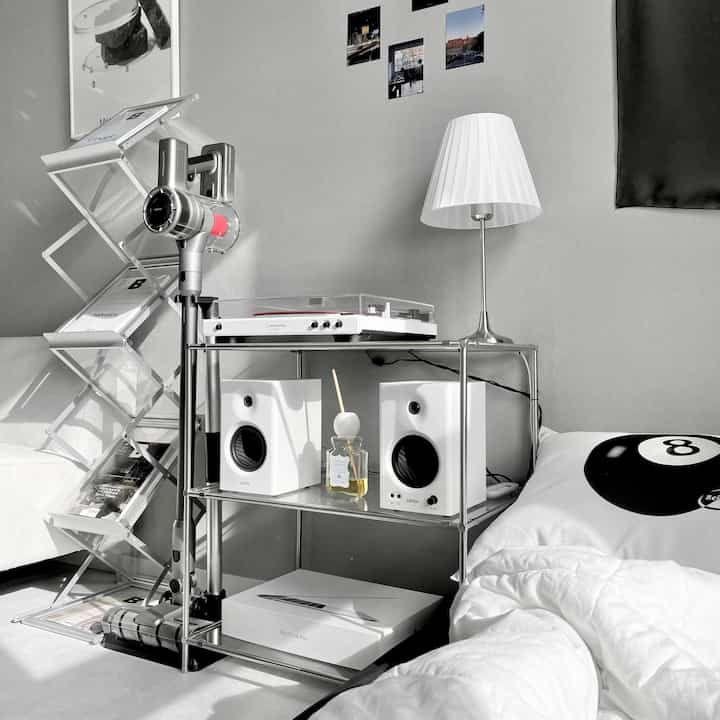Monotone and silver-themed living room featuring a cordless vacuum, turntable, and speakers in a minimal modern interior