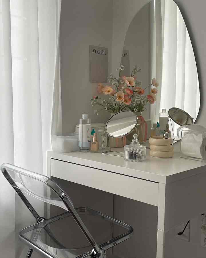 White-toned bedroom featuring a vanity with mirrors and a transparent chair, creating a simple and clean atmosphere