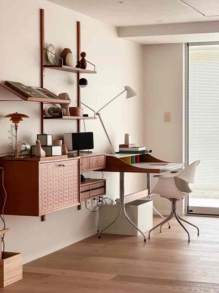 Natural wood-toned study space featuring a Royal System shelving unit and white aluminum blinds, creating a clean, modern atmosphere