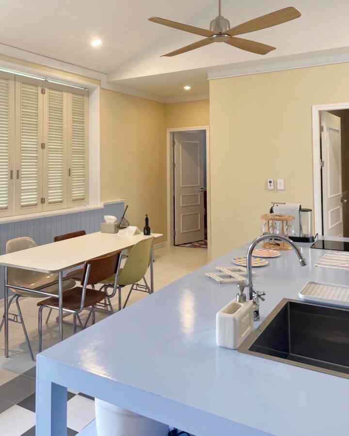 Yellow and sky blue toned kitchen and dining area featuring dining table and chairs in a modern interior