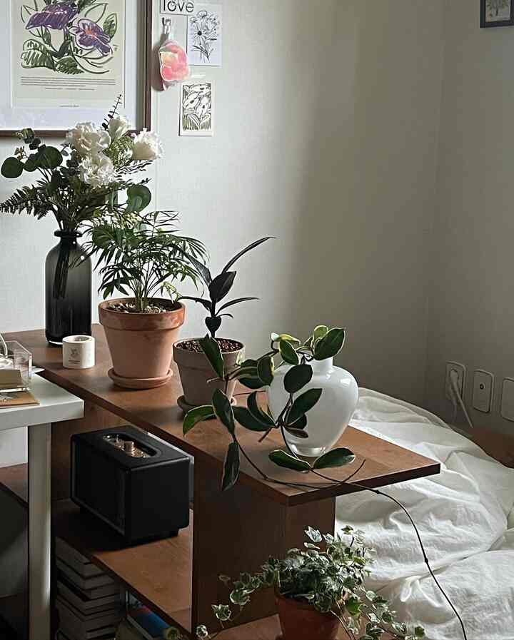 White and wood tone bedroom space featuring white vase and various plants with a natural and simple interior