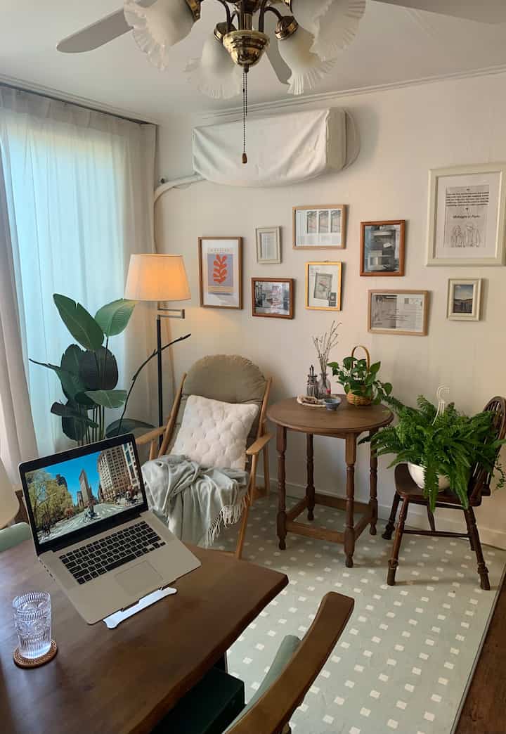 ナチュラルな色調のリビング、木製家具と植物、壁面の額装アート、居心地の良いアームチェアが配置された雰囲気のあるインテリア