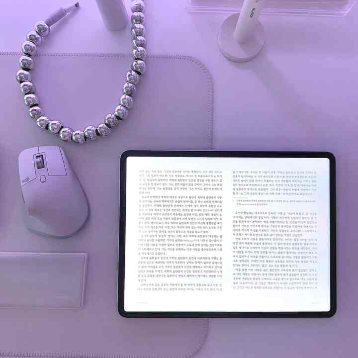 Clean home office setup with an e-reader tablet and wireless mouse on a lavender desk mat