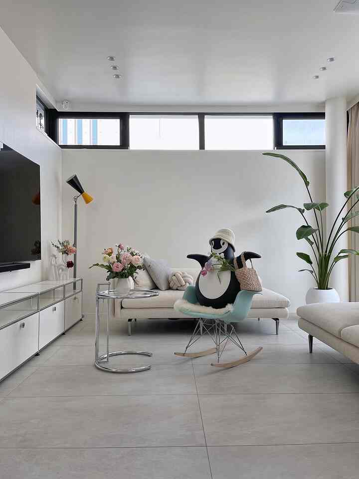 A white and beige toned living room featuring an Eames armchair and fabric sofa in a natural modern style