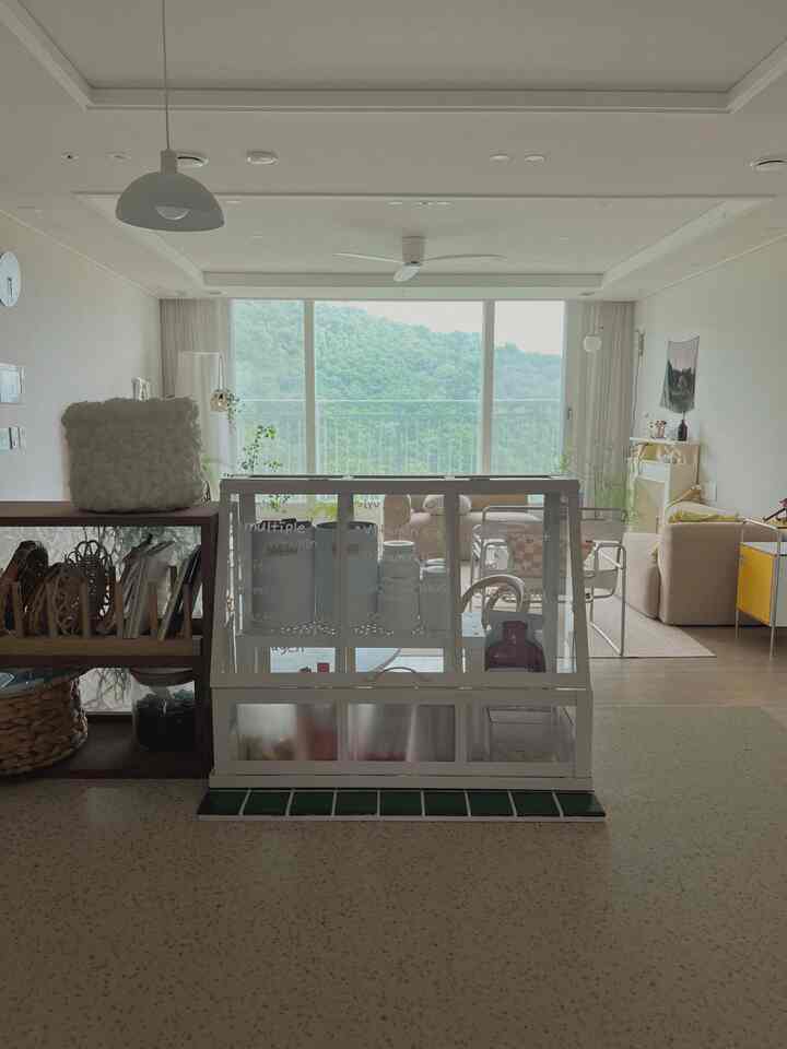 Bright and clean living room in white and natural tones featuring large windows, plants, and modern furniture