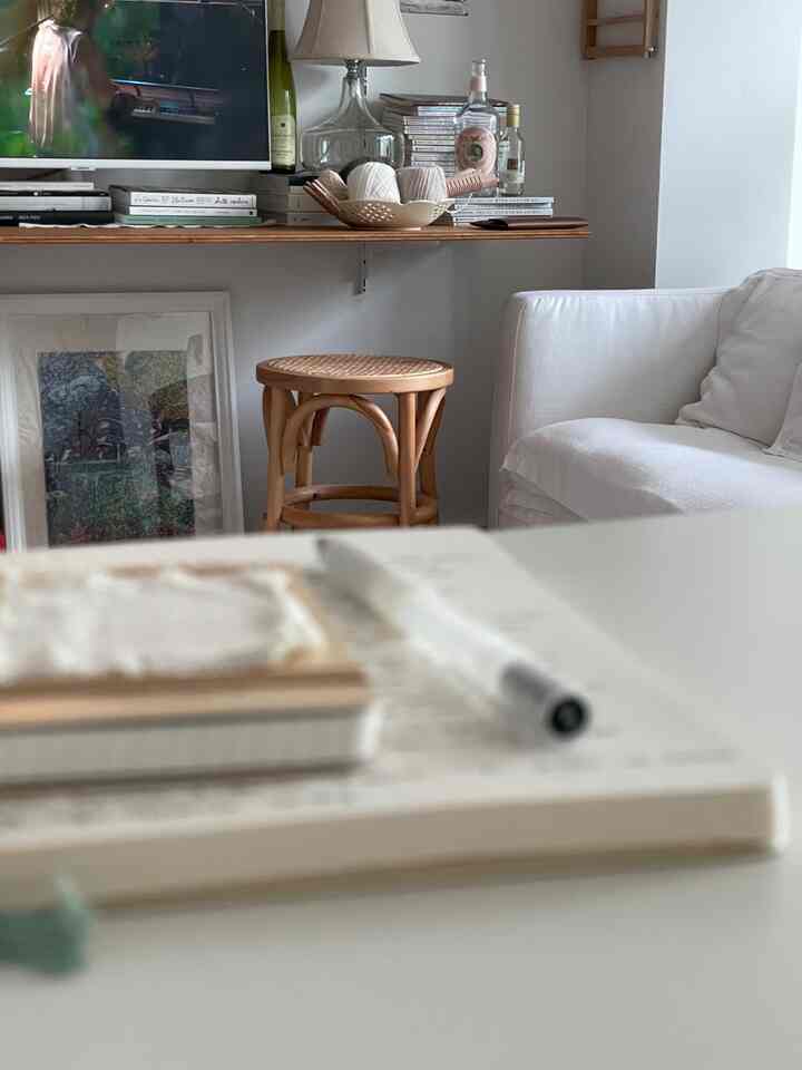 Bright white and wood tone living room featuring a white sofa and small wooden stool creating a cozy atmosphere.