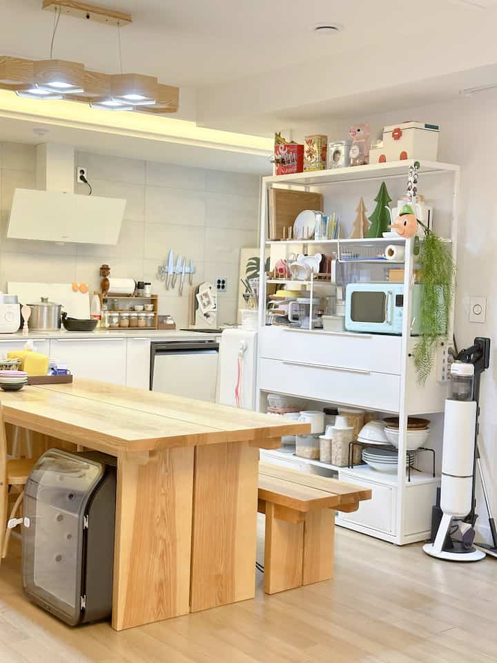 白い壁とナチュラルな木目調のダイニングテーブルが配置された二人暮らし向けのキッチン、すっきりとしたレイアウトで開放感のあるインテリア