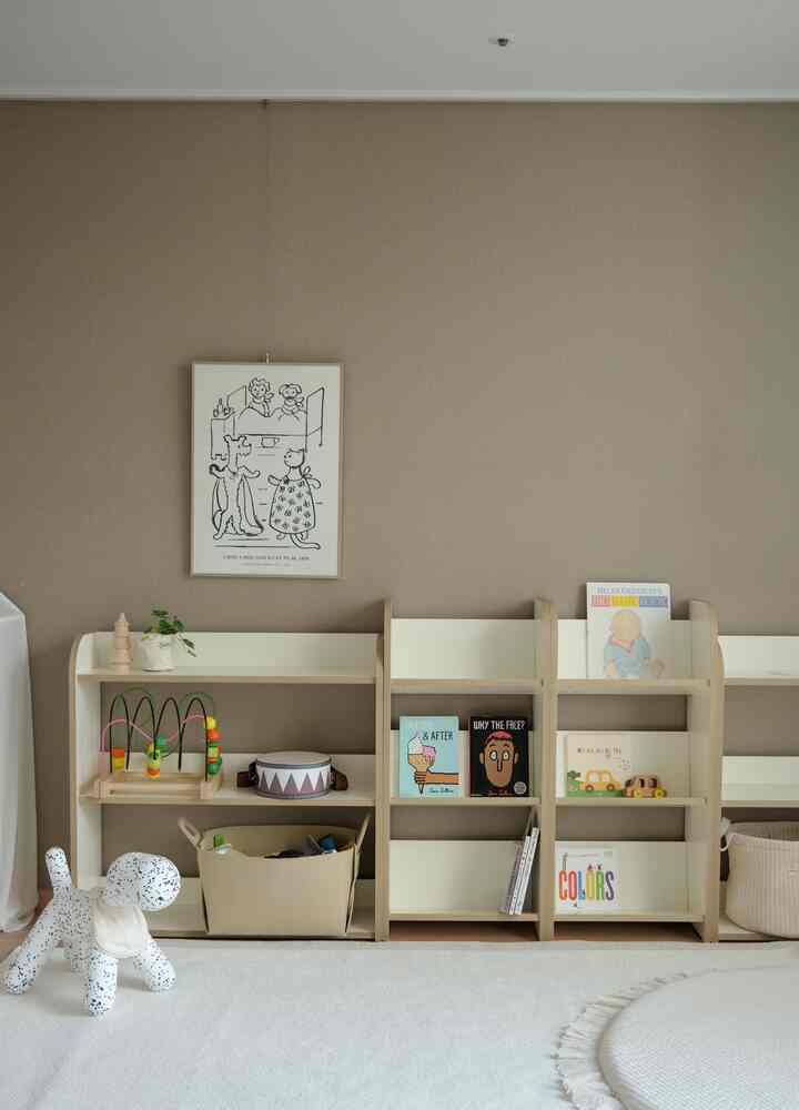 ベージュの壁とナチュラルな木製教材棚が配置された、きちんとした子供部屋のインテリア