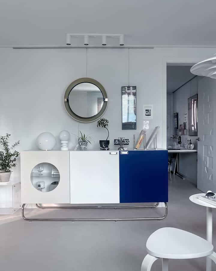 ホワイトとブルーの色調のリビング、ミッドセンチュリーモダンスタイルのBBSキャビネットとヴィンテージのアリバートミラーが印象的なすっきりとした空間