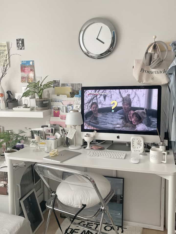 White and transparent-themed home office space featuring a desk with computer and neatly arranged accessories creating a cozy workspace