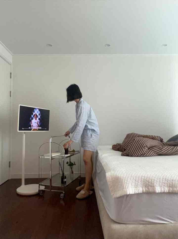 白と茶色のトーンの寝室、ベッドとテレビ台が配置されたシンプルで落ち着いたインテリア