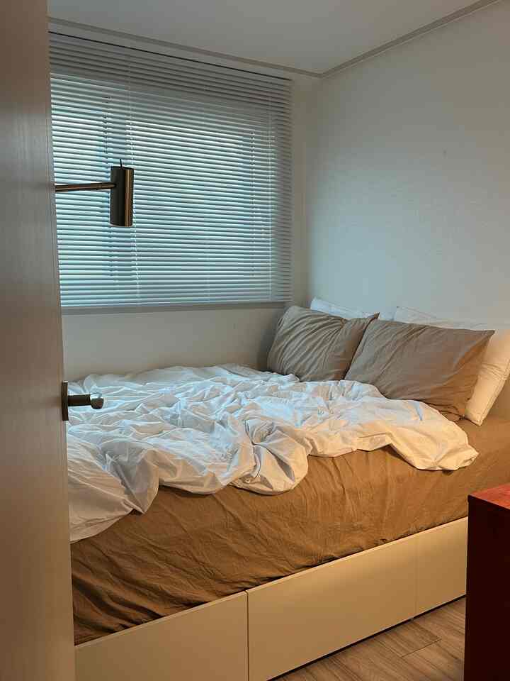 A beige and white toned bedroom with a bed and blinds, creating a cozy and tidy space