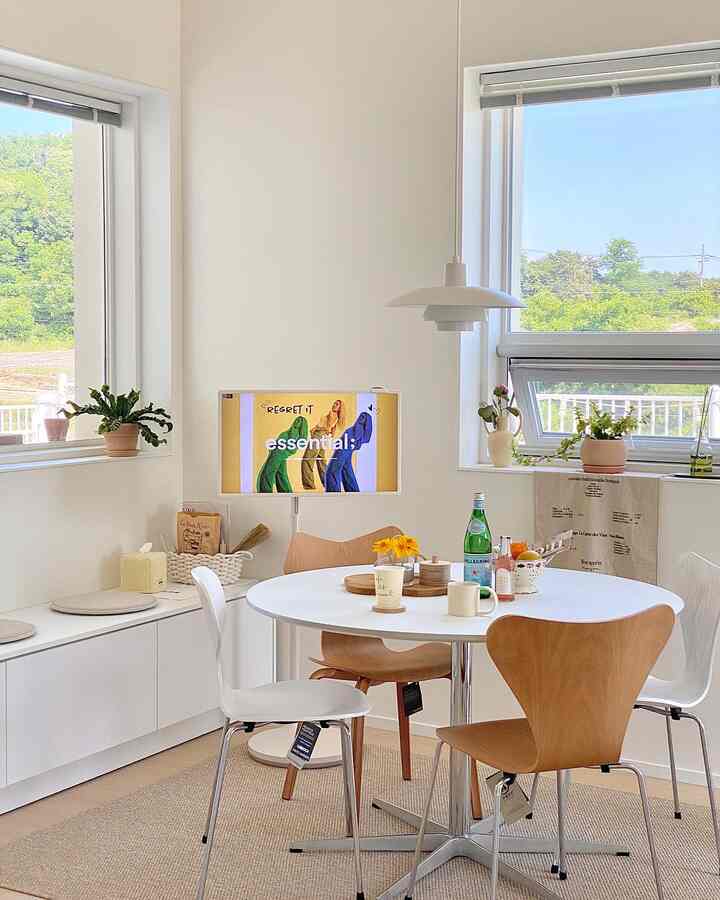 Bright, natural dining room with white and wood tones, featuring pendant lighting and plants