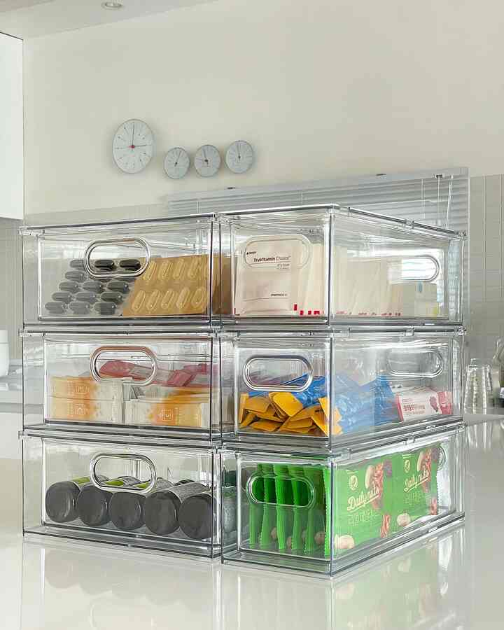 Bright white-toned kitchen space featuring transparent storage boxes neatly organizing supplements in a modern interior