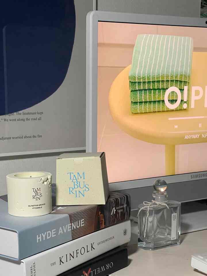 Beige and white toned home office space featuring stacked books with candle and diffuser creating a cozy atmosphere