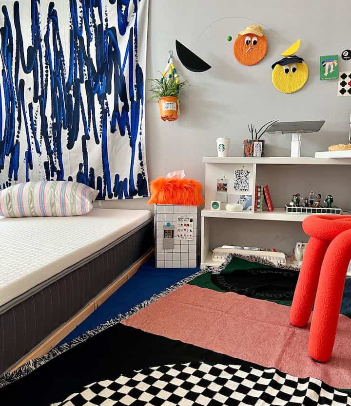 White and blue toned bedroom featuring a mattress, desk, colorful mobile, and rug with a simple modern atmosphere