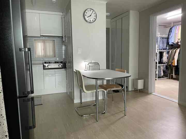 White and wood tone corridor-type apartment kitchen of 22 pyeong, featuring dining table and chairs in a neat modern interior