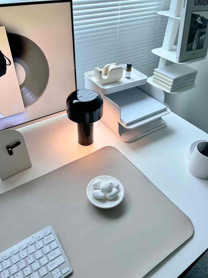 White and simple modern home office featuring an organized desk with monitor stand and unique black lamp
